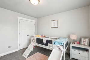 Bedroom with dark colored carpet, a closet, and baseboards