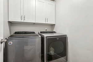 Clothes washing area featuring cabinet space and separate washer and dryer