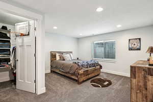 Bedroom with recessed lighting, a closet, dark carpet, a spacious closet, and baseboards