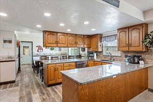 Kitchen featuring brown cabinets, a sink, and a peninsula