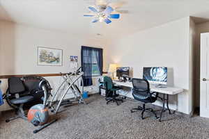 Carpeted home office with a ceiling fan and visible vents