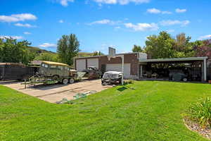 Back of house featuring a garage, a carport, and a lawn