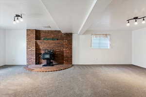 Unfurnished living room featuring carpet and a wood stove