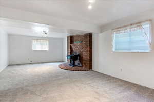 Unfurnished living room with a wood stove and carpet flooring