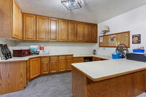 Kitchen with a peninsula, brown cabinets, and light countertops