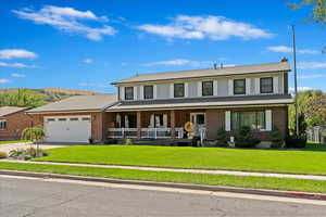 View of front of home featuring brick siding, a porch, concrete driveway, an attached garage, and a front yard