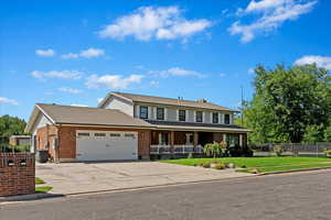 View of front of property with a garage, driveway, brick siding, fence, and a front yard