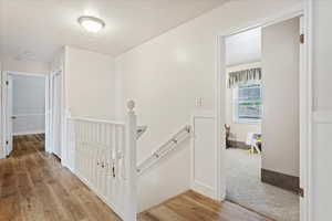 Hall featuring light wood-type flooring, baseboards, and an upstairs landing