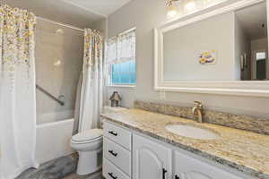 Bathroom with toilet, shower / tub combo with curtain, and vanity