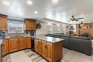 Kitchen featuring open floor plan, brown cabinetry, a sink, and a wood stove