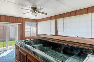 Misc room featuring wooden walls, a ceiling fan, and a hot tub