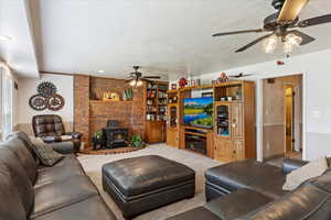 Living area featuring light carpet, a textured ceiling, a wood stove, and a ceiling fan