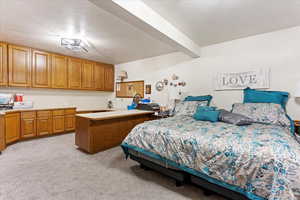 Bedroom featuring light carpet, beam ceiling, and a textured ceiling