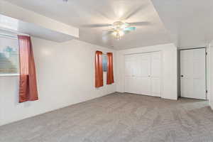 Unfurnished bedroom featuring carpet, ceiling fan, and a closet