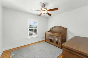 Bedroom with light wood-type flooring, visible vents, baseboards, and a ceiling fan