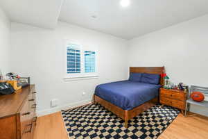 Bedroom with light wood-type flooring, visible vents, and baseboards