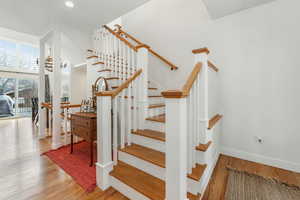 Stairway with a high ceiling, baseboards, a chandelier, and wood finished floors