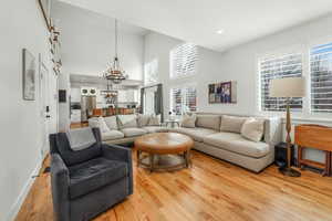 Living area featuring recessed lighting, a notable chandelier, a high ceiling, wood finished floors, and baseboards