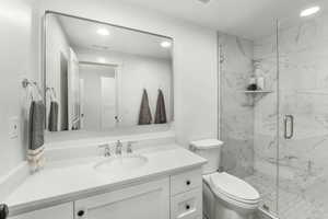 Bathroom with recessed lighting, vanity, and a marble finish shower