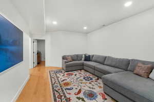 Living room with baseboards, visible vents, wood finished floors, and recessed lighting