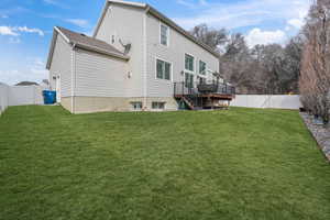 Back of property with a fenced backyard, stairs, a lawn, and a wooden deck