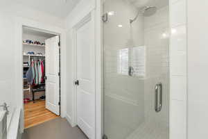 Full bathroom featuring a stall shower, a walk in closet, and tile patterned floors