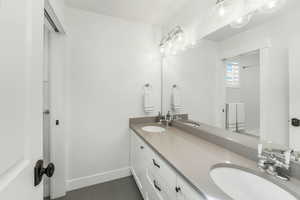 Full bath featuring double vanity, walk in shower, a sink, and baseboards