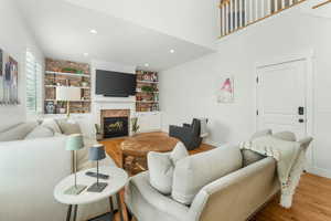 Living room featuring a fireplace with flush hearth, baseboards, wood finished floors, and recessed lighting