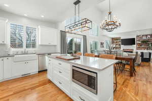 Kitchen featuring a breakfast bar, hanging light fixtures, appliances with stainless steel finishes, open floor plan, and a sink