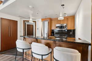 Kitchen featuring stainless steel appliances, tasteful backsplash, a breakfast bar, and hanging light fixtures