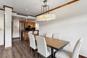 Dining area featuring crown molding and dark wood-style floors