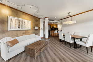 Living area featuring ornamental molding, wood finished floors, rail lighting, and baseboards