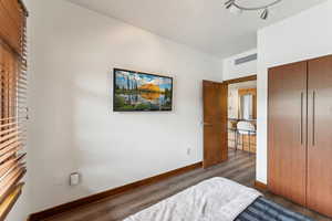 Bedroom featuring wood finished floors, baseboards, and a closet