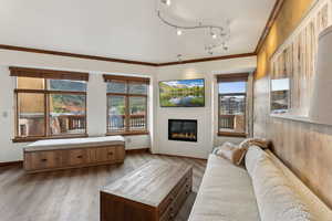 Living room with a glass covered fireplace, plenty of natural light, crown molding, and baseboards