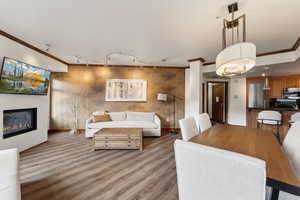 Dining room featuring ornamental molding, track lighting, baseboards, a glass covered fireplace, and light wood finished floors