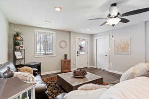 Living area with a ceiling fan, recessed lighting, dark wood finished floors, and baseboards