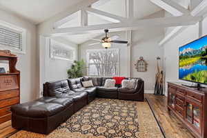 Living area featuring lofted ceiling, a ceiling fan, baseboards, and wood finished floors