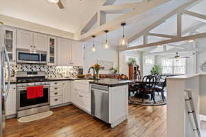 Kitchen with a peninsula, ceiling fan, vaulted ceiling with beams, and stainless steel appliances