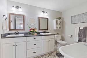 Full bath with a freestanding tub, a sink, toilet, and double vanity