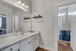 Full bath with ensuite bathroom, vanity, wood finished floors, a shower with curtain, and baseboards