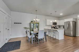 Dining space with baseboards, visible vents, light wood finished floors, and an inviting chandelier