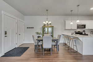 Dining space featuring a chandelier, baseboards, visible vents, and light wood finished floors