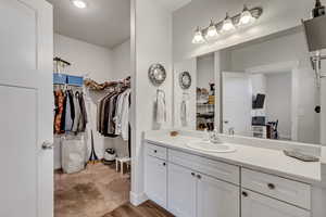 Bathroom featuring a walk in closet, vanity, baseboards, and wood finished floors