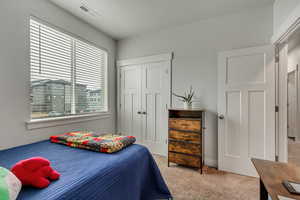 Bedroom with light colored carpet, a closet, and visible vents