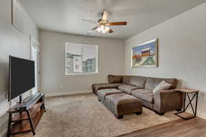 Living area with baseboards, visible vents, and a ceiling fan