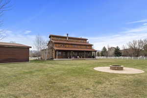 Rear view of house with fence, a fire pit, a deck, and a lawn