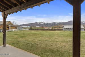 View of yard with an outbuilding, a rural view, fence, and a mountain view