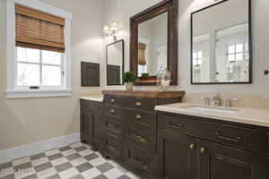 Bathroom featuring a sink, baseboards, a tile shower, tile patterned floors, and double vanity