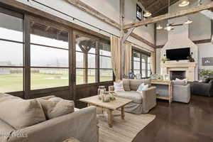 Living area featuring wooden ceiling, finished concrete floors, high vaulted ceiling, and a fireplace