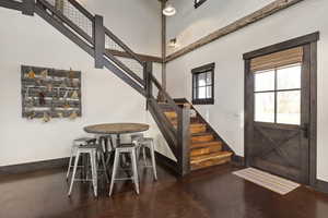 Foyer featuring a high ceiling, baseboards, concrete floors, and stairway